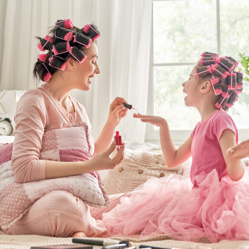 Mother and daughter in pink painting fingernails at home