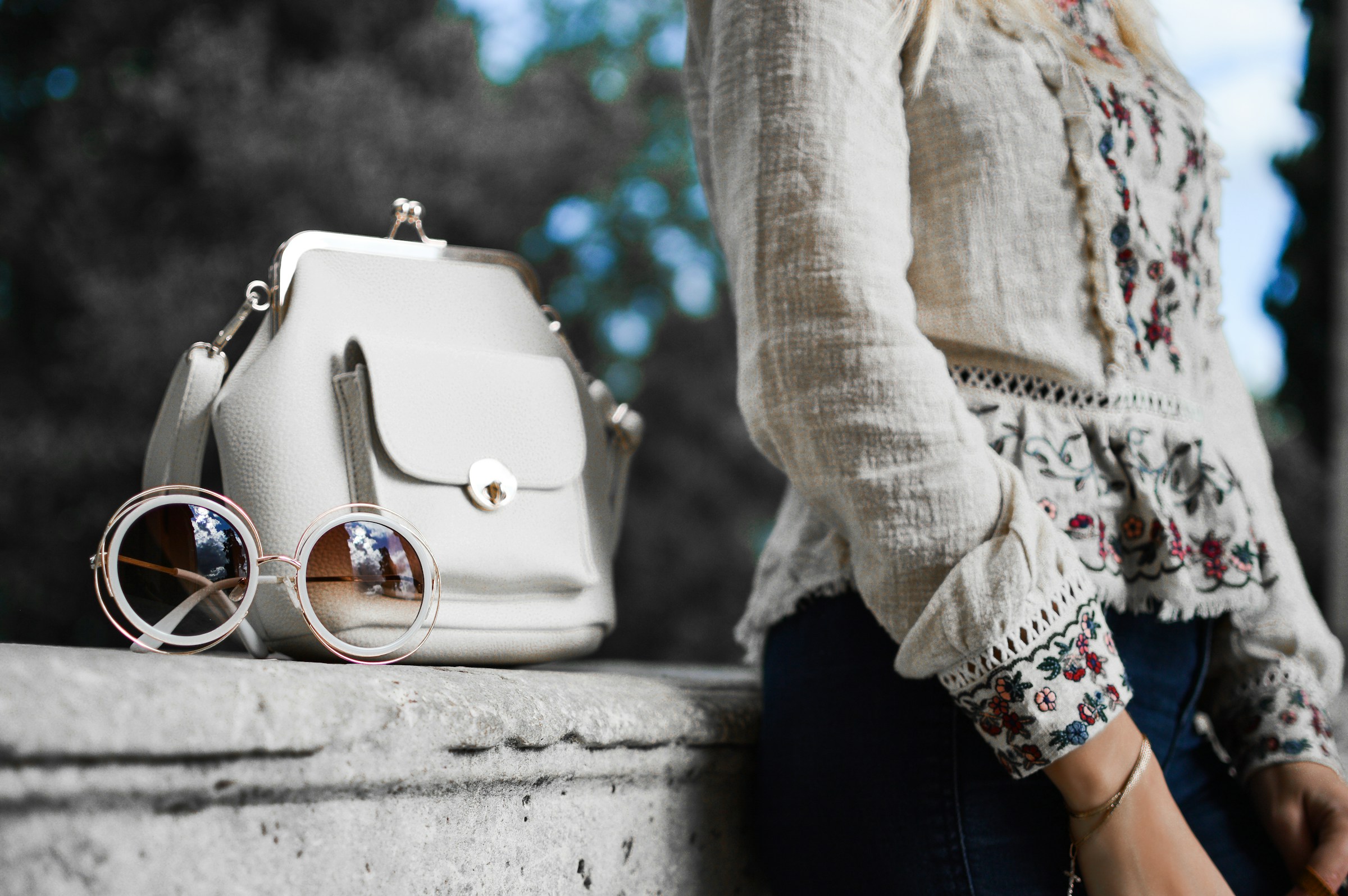 a clothing influencer standing next to a bag and sunglasses